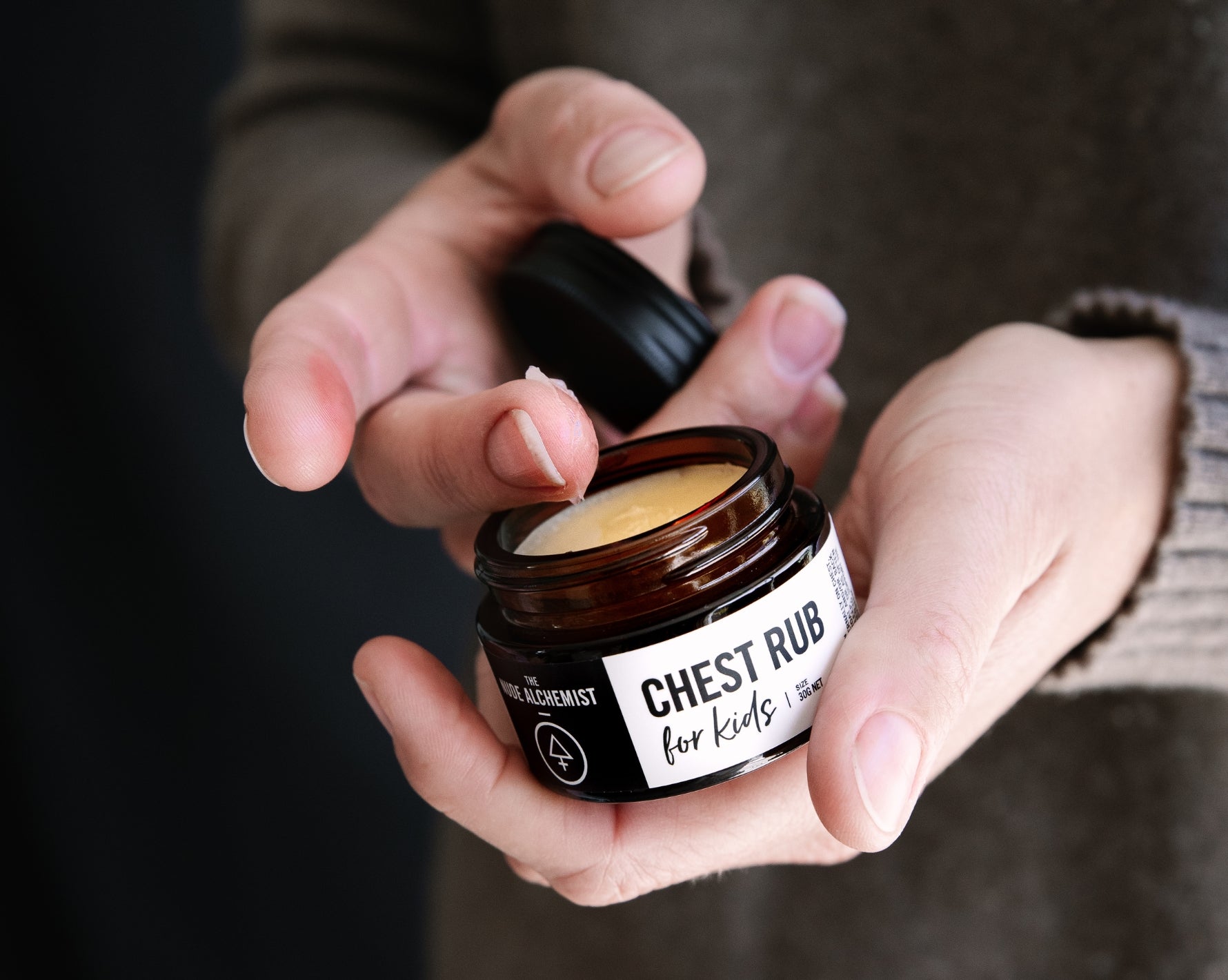Person holding a jar of 'Chest Rub' by The Nude Alchemist