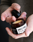 Person holding a jar of 'Chest Rub' by The Nude Alchemist