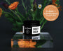 Booty Balm jar with flowers and 'Clean + Conscious Awards' badge on a reflective surface