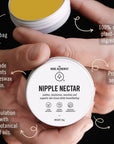 A person's hands holding a round white jar labeled 'NIPPLE NECTAR' by 'THE NUDE ALCHEMIST' against a dark background, with several callout text overlays describing product features.